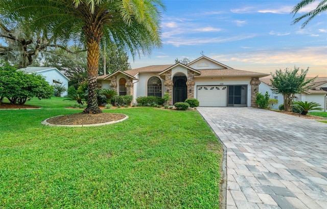 ranch-style house with a garage, stone siding, decorative driveway, and a front yard