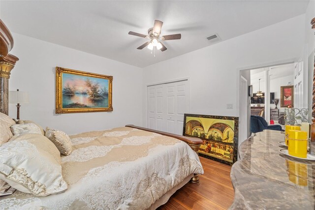 bedroom featuring a closet, wood finished floors, visible vents, and a ceiling fan