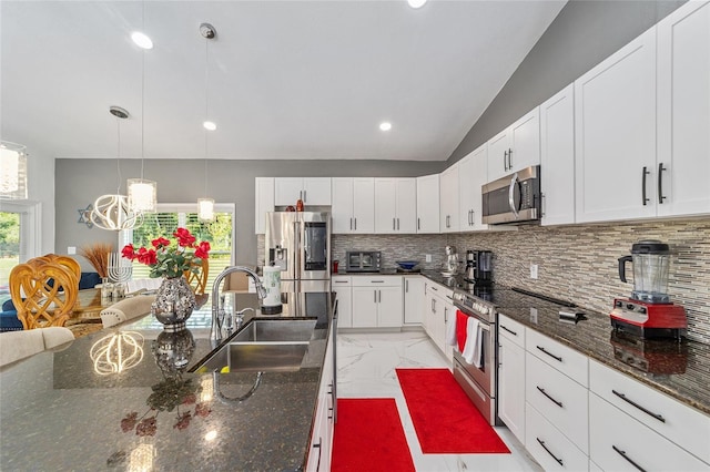 kitchen featuring tasteful backsplash, white cabinets, appliances with stainless steel finishes, marble finish floor, and a sink