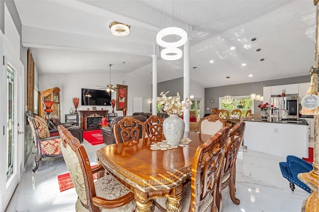 dining room featuring lofted ceiling with beams, marble finish floor, a fireplace, and a ceiling fan