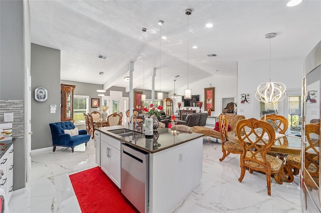 kitchen with dark countertops, open floor plan, a sink, and stainless steel dishwasher