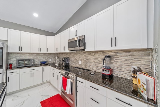 kitchen featuring vaulted ceiling, marble finish floor, appliances with stainless steel finishes, and backsplash