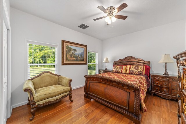 bedroom with ceiling fan, wood finished floors, visible vents, and baseboards