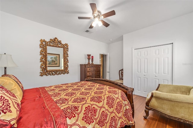 bedroom with ceiling fan, lofted ceiling, wood finished floors, visible vents, and a closet