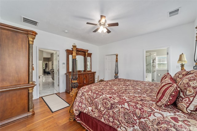 bedroom with ceiling fan, wood finished floors, visible vents, and connected bathroom