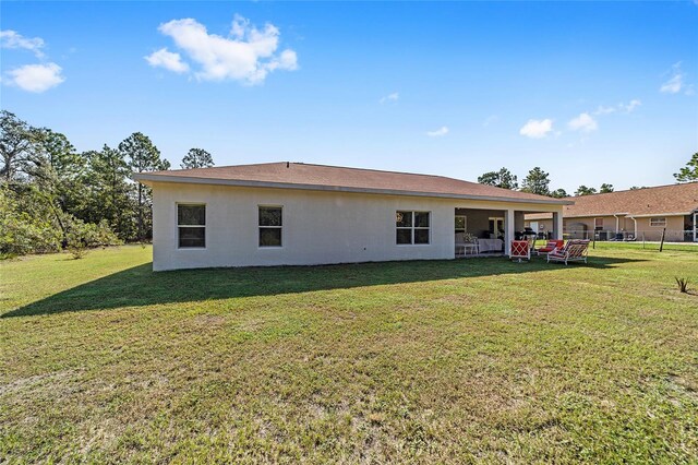 rear view of property with a yard and stucco siding