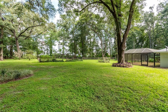 view of yard featuring a lanai, a detached carport, and fence