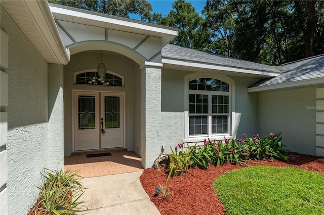 entrance to property with a shingled roof and stucco siding