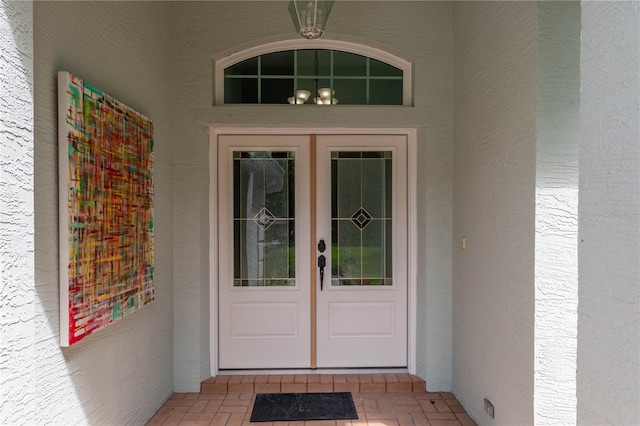 view of exterior entry featuring french doors and stucco siding