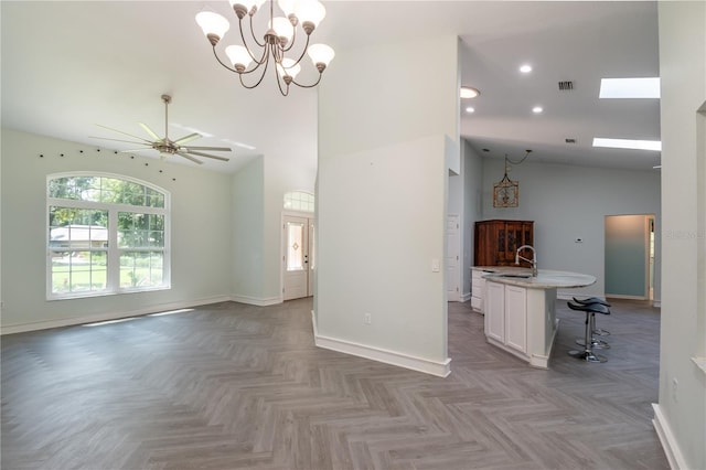 unfurnished living room with ceiling fan with notable chandelier, a skylight, sink, high vaulted ceiling, and light parquet flooring