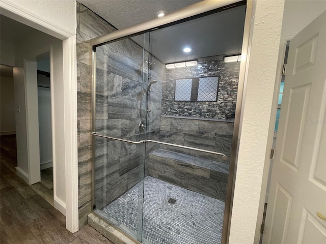 bathroom featuring a textured ceiling, wood-type flooring, and a shower with door