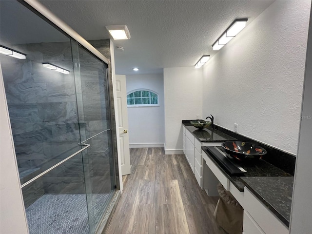 bathroom with hardwood / wood-style floors, vanity, a textured ceiling, and a shower with shower door