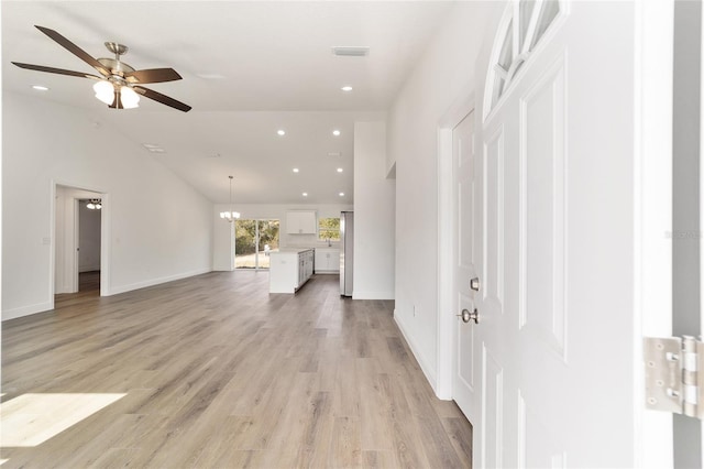 interior space featuring lofted ceiling, ceiling fan with notable chandelier, and light hardwood / wood-style flooring