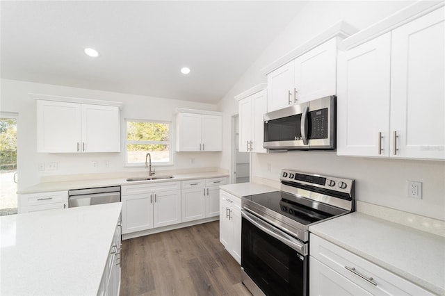 kitchen with dark wood-type flooring, lofted ceiling, sink, appliances with stainless steel finishes, and white cabinets