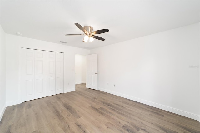 unfurnished bedroom with ceiling fan, hardwood / wood-style floors, and a closet