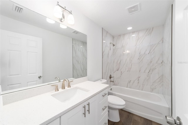 full bathroom featuring vanity, tiled shower / bath combo, wood-type flooring, and toilet