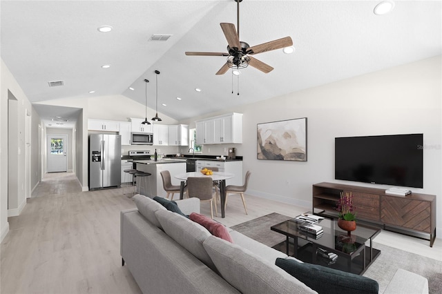 living room with ceiling fan, lofted ceiling, light wood-type flooring, and sink