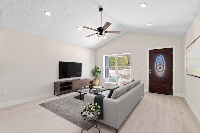 living room with a textured ceiling, light hardwood / wood-style floors, vaulted ceiling, and ceiling fan