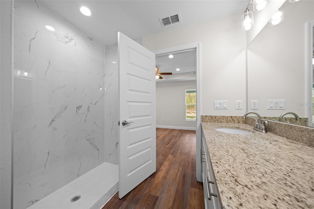 bathroom featuring hardwood / wood-style flooring, a tile shower, and vanity