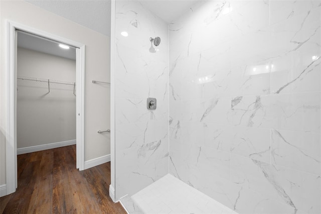 bathroom with tiled shower and hardwood / wood-style floors