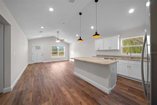 kitchen with white cabinetry, pendant lighting, a center island, and light stone counters