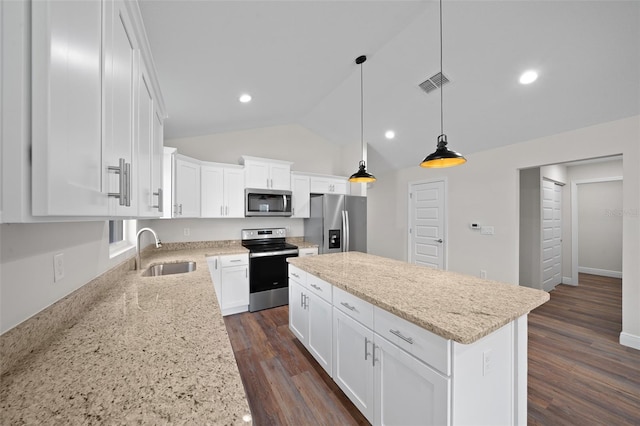 kitchen with appliances with stainless steel finishes, light stone counters, white cabinets, a kitchen island, and sink