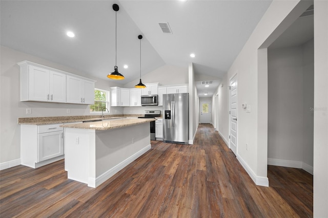 kitchen featuring appliances with stainless steel finishes, white cabinets, and hanging light fixtures