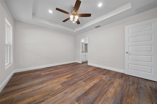 spare room with ceiling fan, a raised ceiling, and dark hardwood / wood-style floors