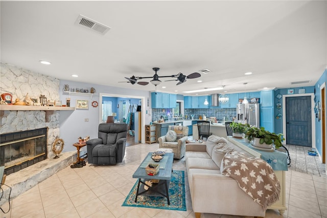 tiled living room featuring ceiling fan and a stone fireplace