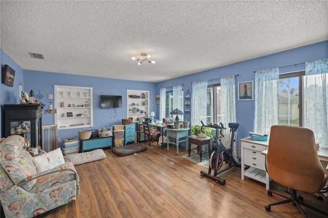 home office featuring a textured ceiling, built in features, and hardwood / wood-style floors