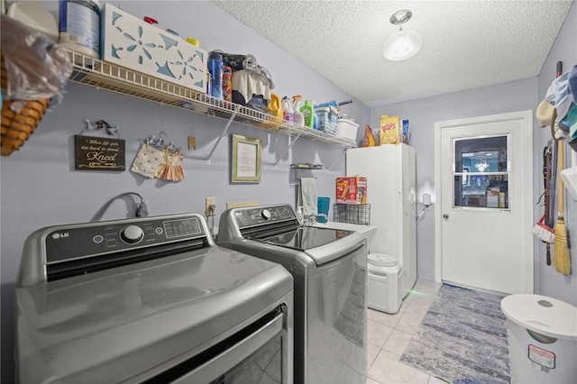 laundry area with a textured ceiling, independent washer and dryer, and light tile patterned floors