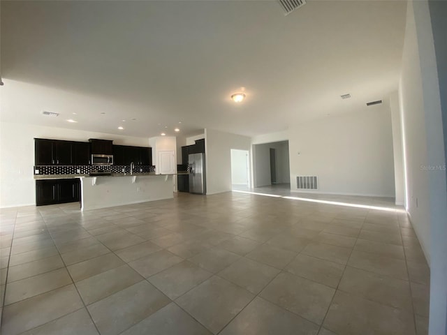 unfurnished living room with sink and light tile patterned floors