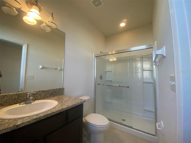 bathroom with tile patterned flooring, a shower with door, toilet, and vanity