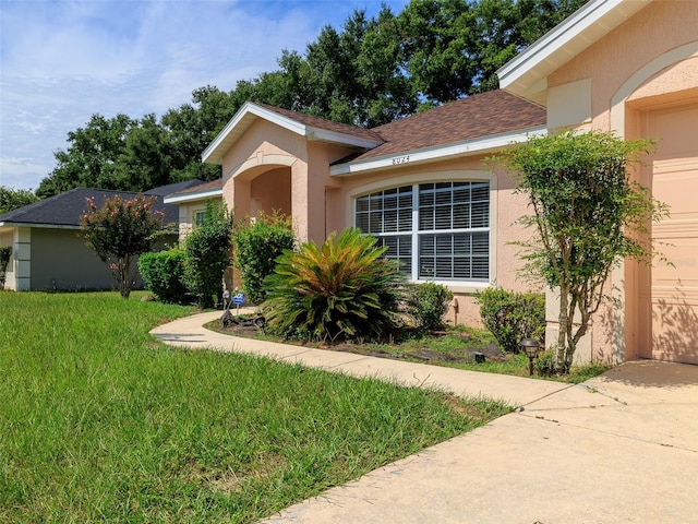 ranch-style home with a garage and a front lawn