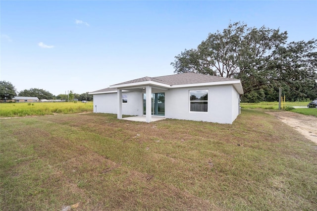 rear view of property featuring a lawn and a patio