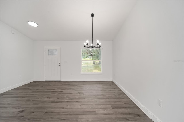 unfurnished dining area featuring dark hardwood / wood-style floors, an inviting chandelier, and lofted ceiling