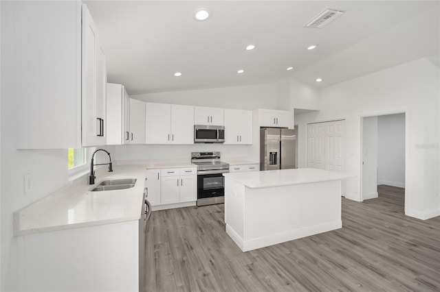 kitchen featuring sink, a kitchen island, lofted ceiling, white cabinets, and appliances with stainless steel finishes