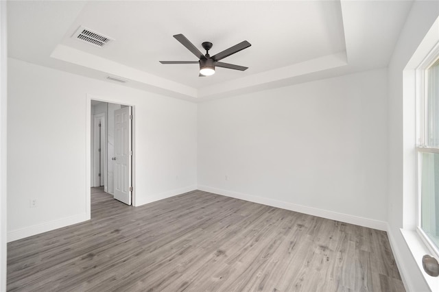 spare room featuring a healthy amount of sunlight, light hardwood / wood-style floors, and a tray ceiling