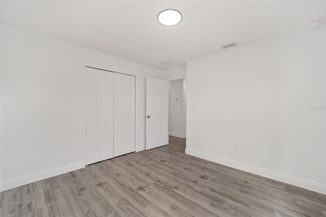 unfurnished bedroom with a closet and light hardwood / wood-style flooring