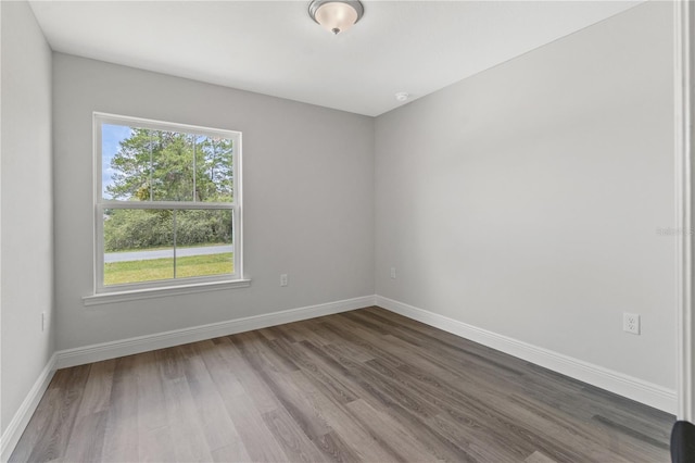 spare room with baseboards and wood finished floors