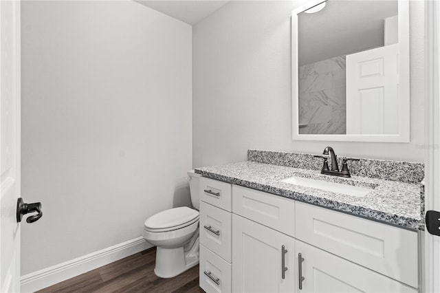 bathroom featuring vanity, toilet, wood finished floors, and baseboards