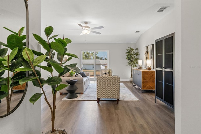 living area featuring ceiling fan, visible vents, baseboards, and wood finished floors