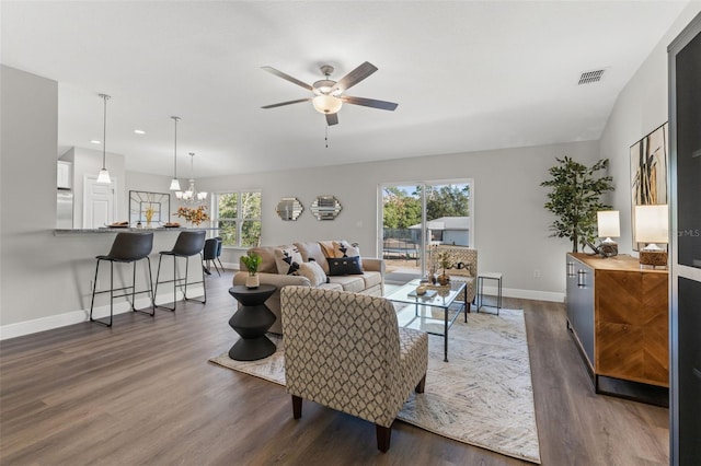 living room with ceiling fan with notable chandelier, visible vents, dark wood-style flooring, and baseboards