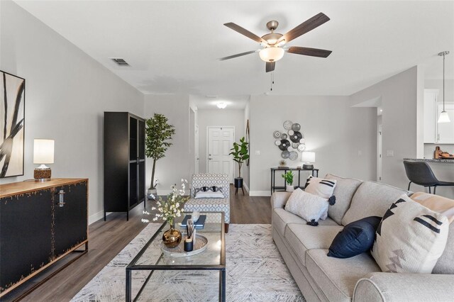 living area with ceiling fan, visible vents, baseboards, and wood finished floors