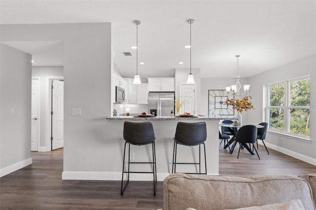 kitchen featuring visible vents, dark wood finished floors, a breakfast bar, appliances with stainless steel finishes, and white cabinetry