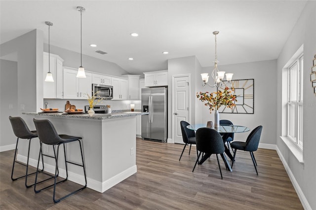 kitchen with visible vents, a peninsula, stainless steel appliances, an inviting chandelier, and white cabinetry