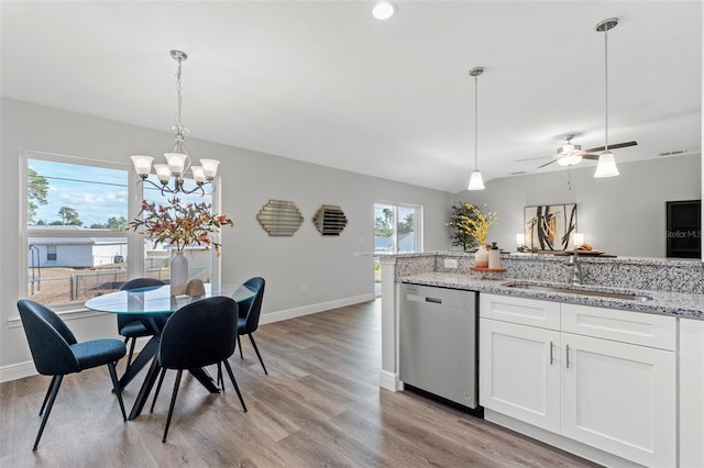 kitchen featuring a sink, hanging light fixtures, white cabinets, stainless steel dishwasher, and light wood-type flooring