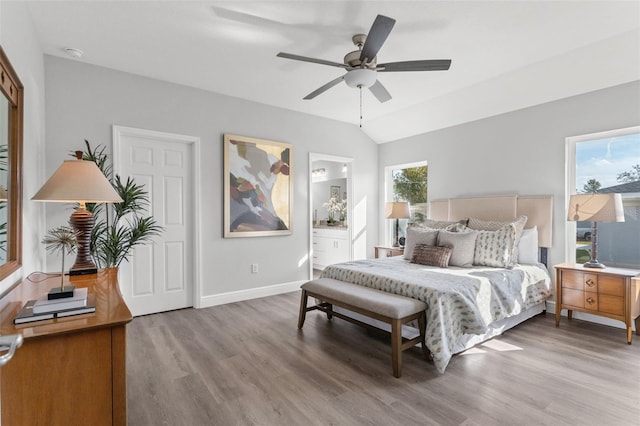 bedroom with baseboards, lofted ceiling, ensuite bathroom, wood finished floors, and a ceiling fan