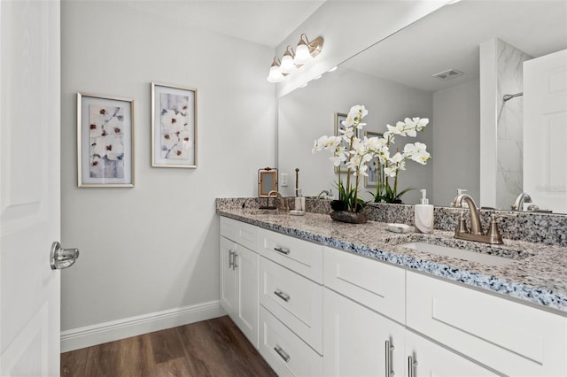 full bath with a sink, visible vents, baseboards, and wood finished floors