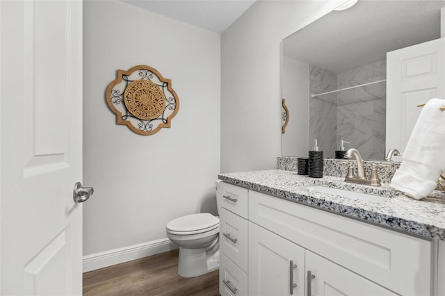 full bath featuring a marble finish shower, baseboards, toilet, wood finished floors, and vanity